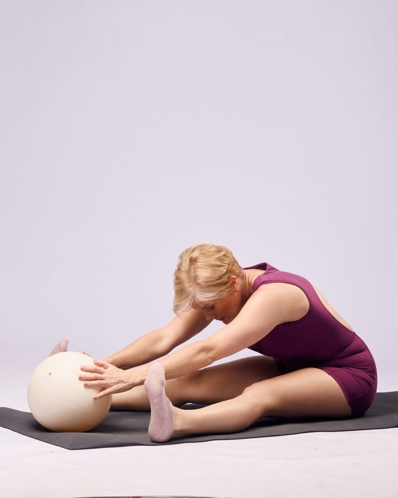 Adriana estirándose hacia la pelota de pilates